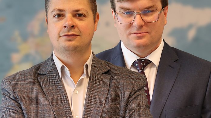 Dr Lachowski i dr Piątkowski na tle mapy świata.