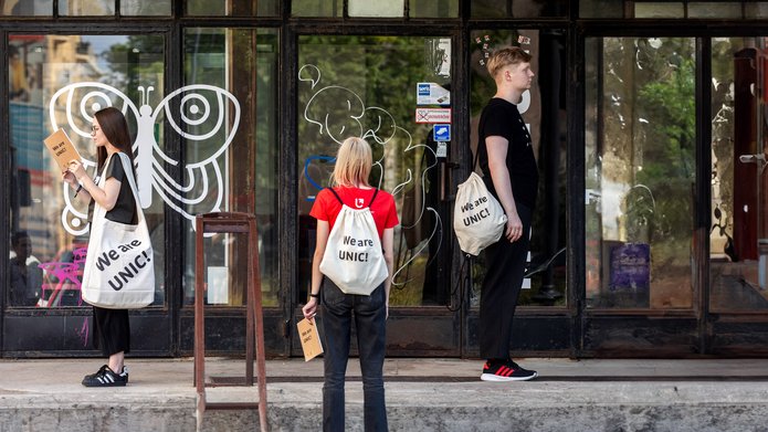 Troje studentów stojących na schodach z torbami i plecakami z projektu UNIC