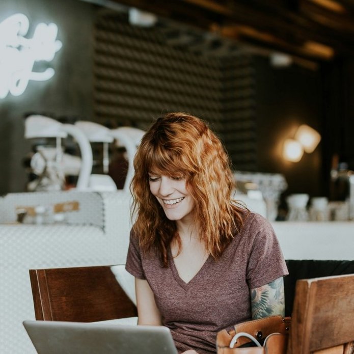 Uśmiechnięta dziewczyna używa laptopa. Zdjęcie poglądowe.