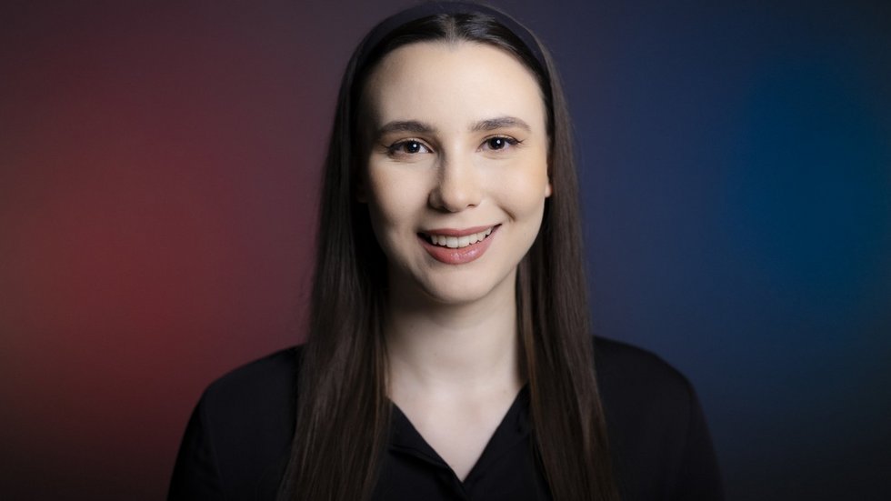 Dziewczyna z długimi ciemnymi włosami w opasce na głowie na tle fioletowo granatowej ściany