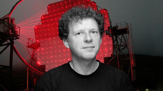 Professor Julian Sitarek against the background of the Cherenkov Telescope illuminated by red lasers