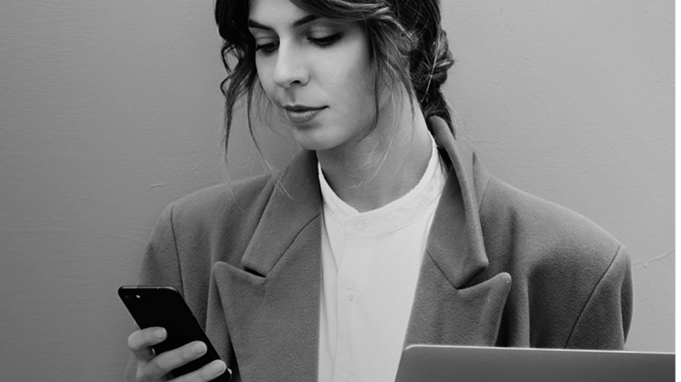 młoda kobieta spoglądająca na trzymany w dłoni telefon