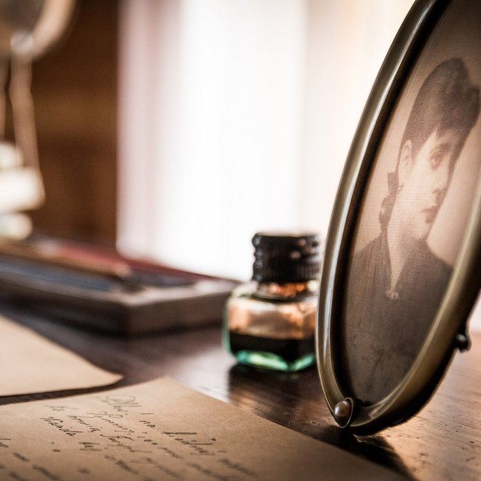 Listy, butelka z atramentem i zdjęcie kobiety na biurku