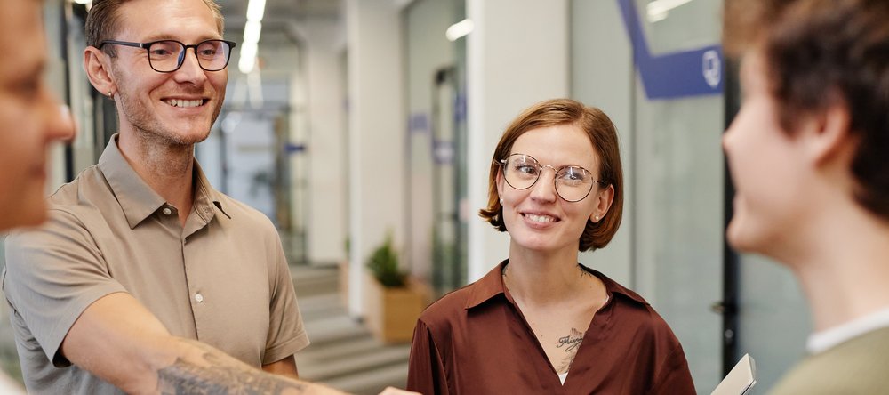 A colour photo illustrating a meeting of young smiling women and men