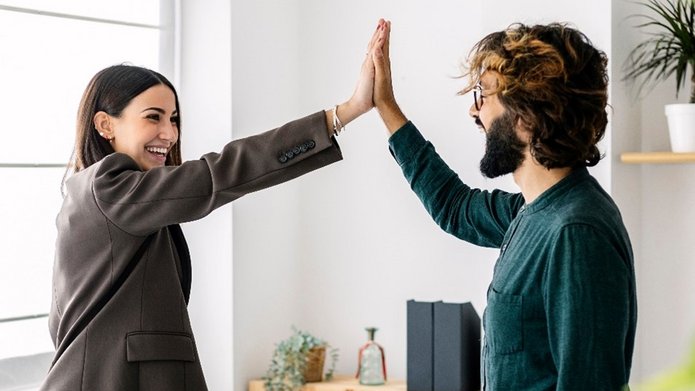 A smiling woman giving high-five to her happy friend