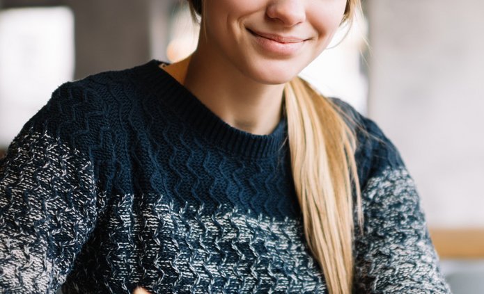 Kobieta w granatowym swetrze robiąca notatatki