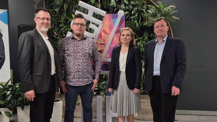 zdjęcie z konferencji, przedstawiające 4 osoby stojące obok siebie 