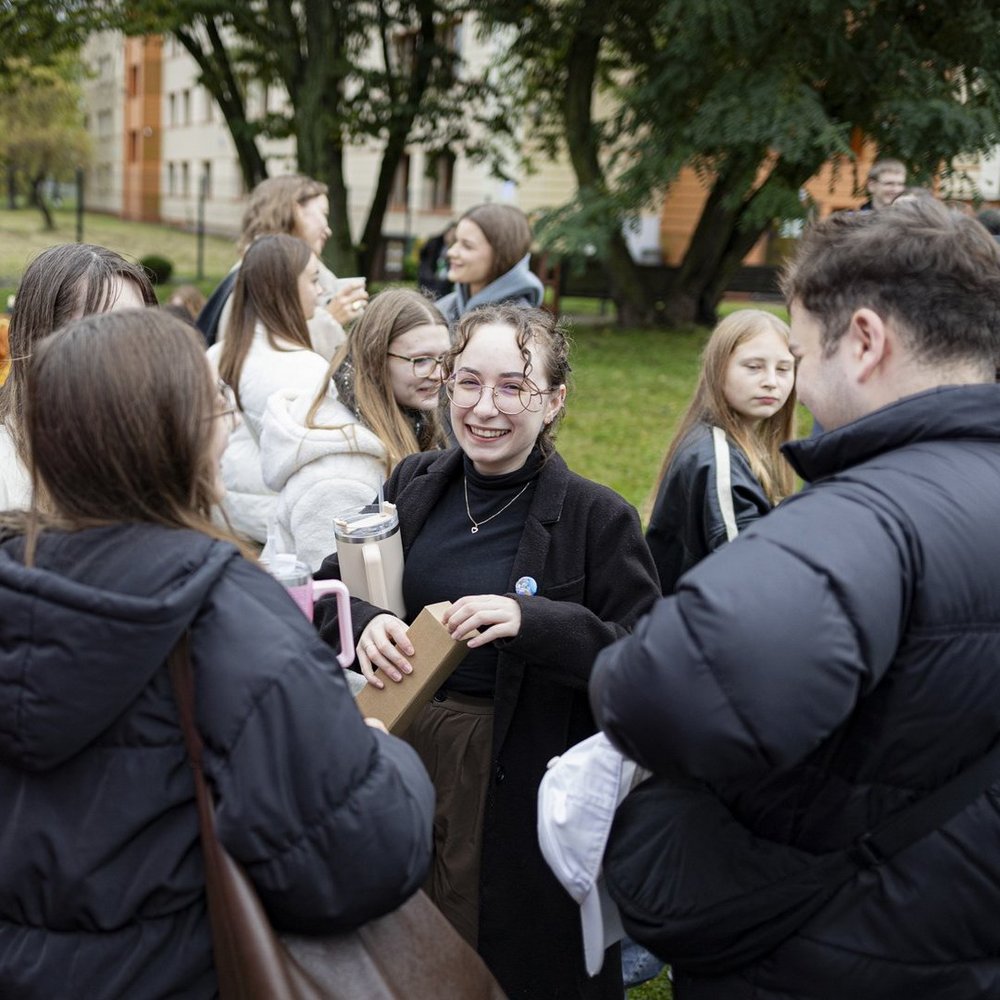 A colour photo of smiling students during a picnic at the UniLodz campus