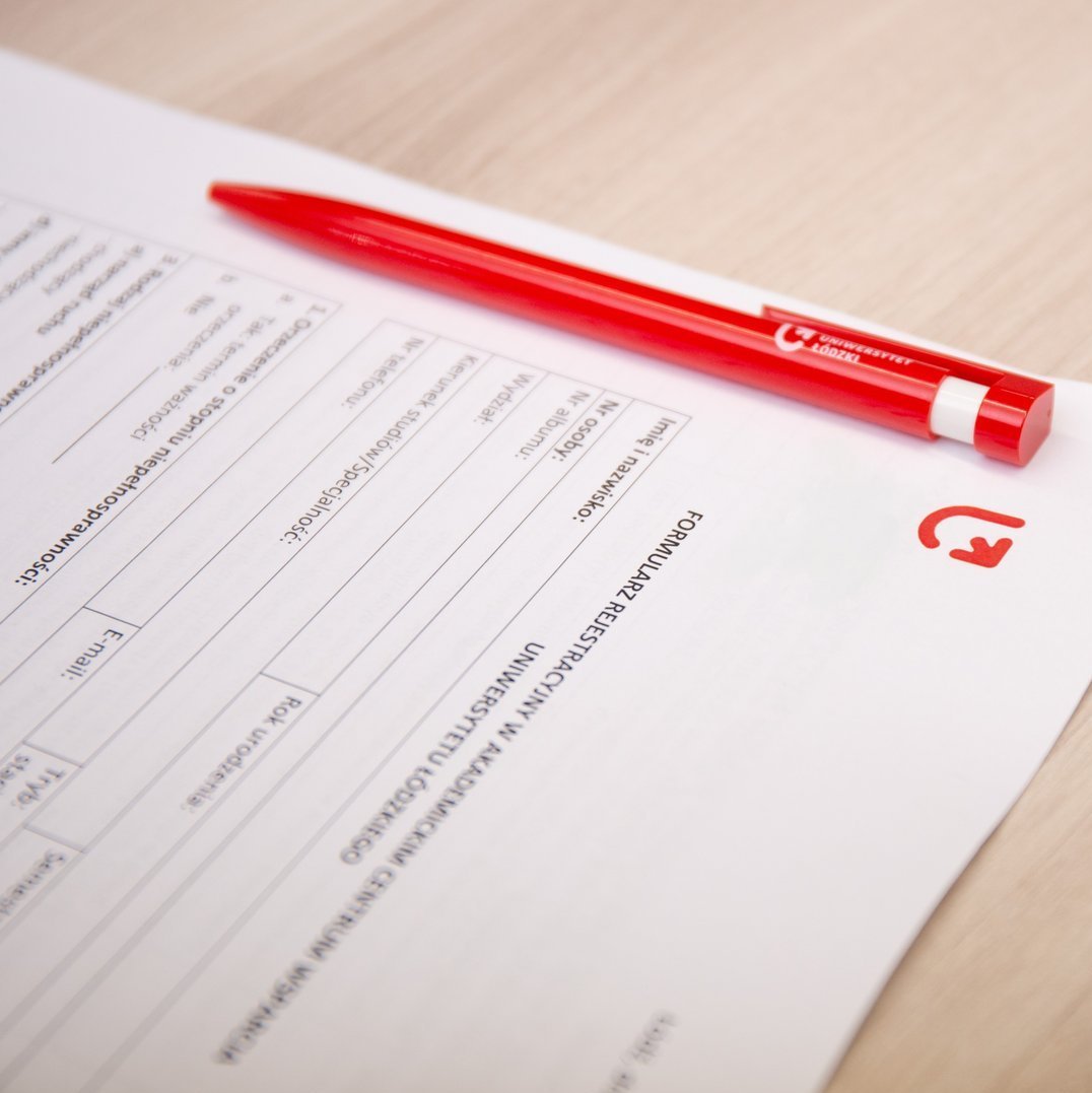 Zdjęcie formularza rejestracyjnego, obok leży czerwony długopis z napisem Uniwersytet Łódzki