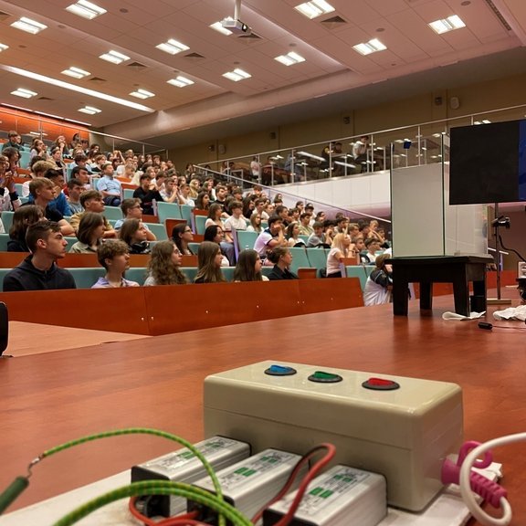 aula na której są uczestnicy spotkania, oraz na ladzie wykładowej jest urządzenie