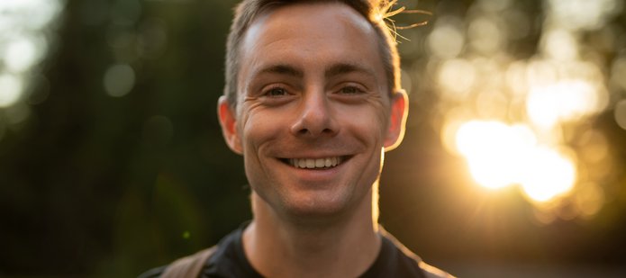 Uśmiechnięty młody mężczyzna na tle drzew