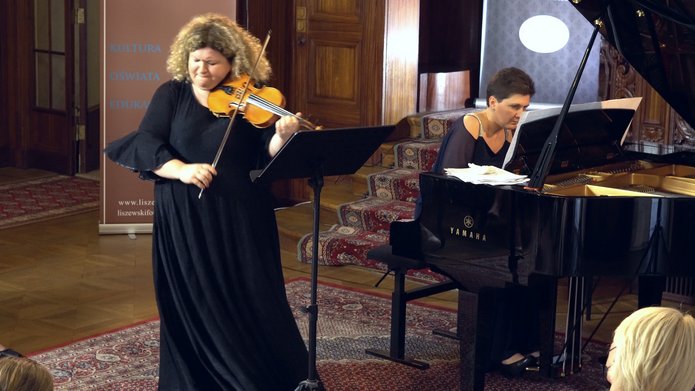 Kobieta w czarnej sukni grajaca na skrzypcach oraz kobieta grająca na fortepianie