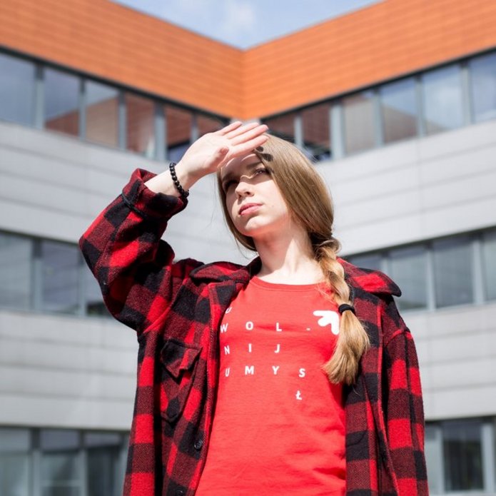 dziewczyna na tle WZ patrzy w stronę Słońca, osłania oczy