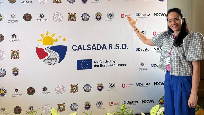 a woman standing in front of a backdrop displaying institutional logos