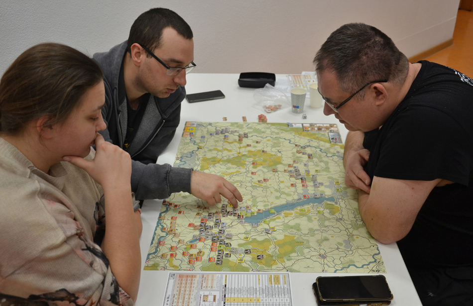 osoby uczestniczące w grze siedzące wokół stołu z grą osoby uczestniczące w grze siedzące wokół stołu z grą