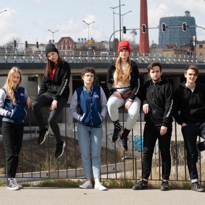 young people are standing at the railway station fence