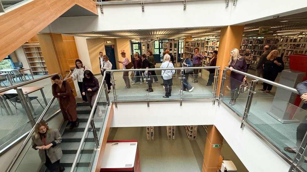 a group of people walking through the University of Lodz Library building