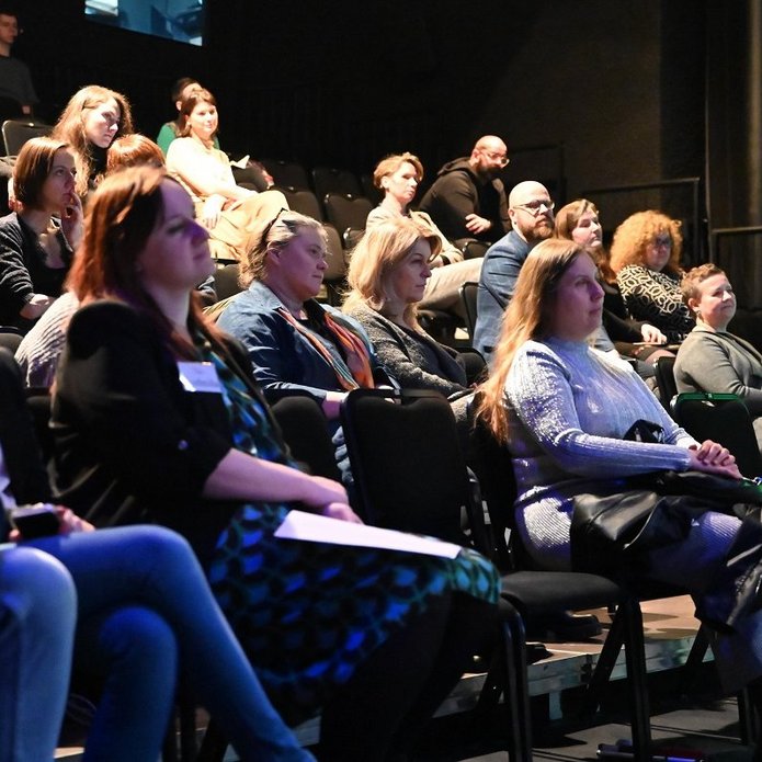 kilkanaście osób siedzi na widowni 