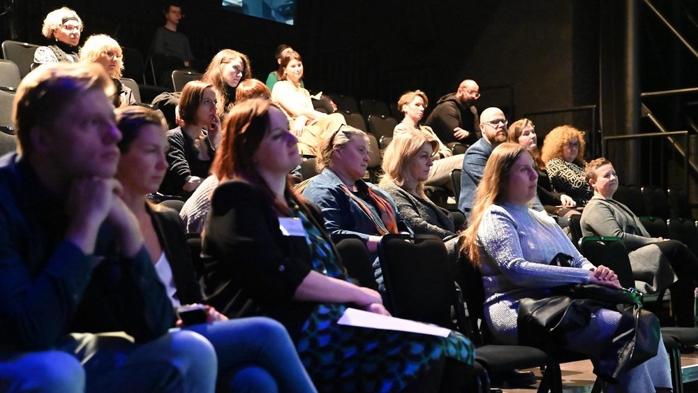 kilkanaście osób siedzi na widowni 