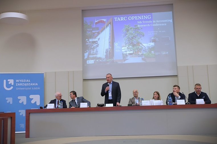 otwarcie konferencji, uczestnicy z astołem prezydialnym, na tle slajdu z widokiem na front budynku wydziału zarządzania 