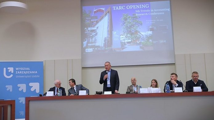 otwarcie konferencji, uczestnicy z astołem prezydialnym, na tle slajdu z widokiem na front budynku wydziału zarządzania 