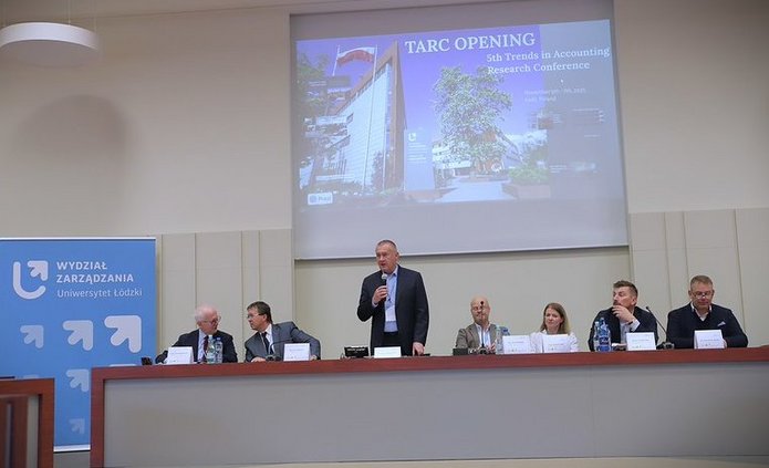otwarcie konferencji, uczestnicy z astołem prezydialnym, na tle slajdu z widokiem na front budynku wydziału zarządzania 