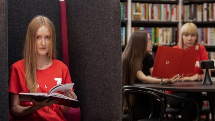 studenci w czytelni, jedna dziewczyna siedzi w fotelu, 3 osoby przy stole