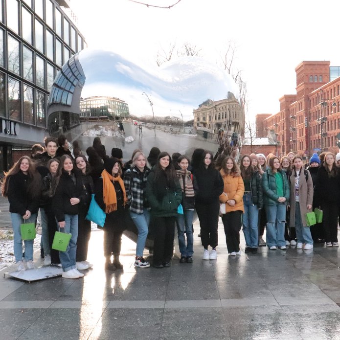 A group of high school students on the background of a silver heart in Lodz