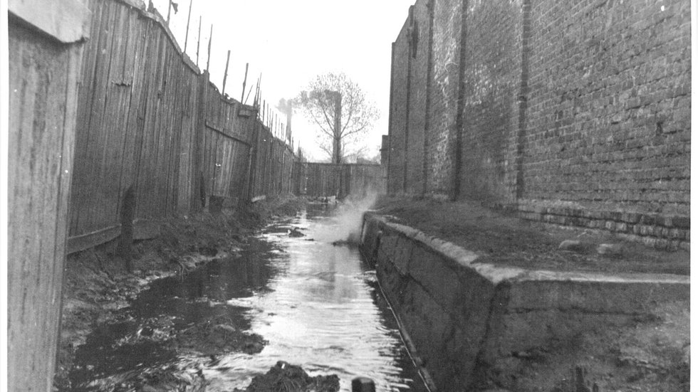 An archival photo of the Bałutka river flowing along the fences