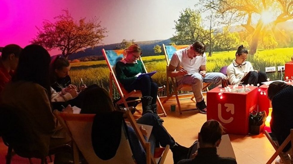 grupa osób siedząca na leżakach w przyciemnionej sali szkoleniowej