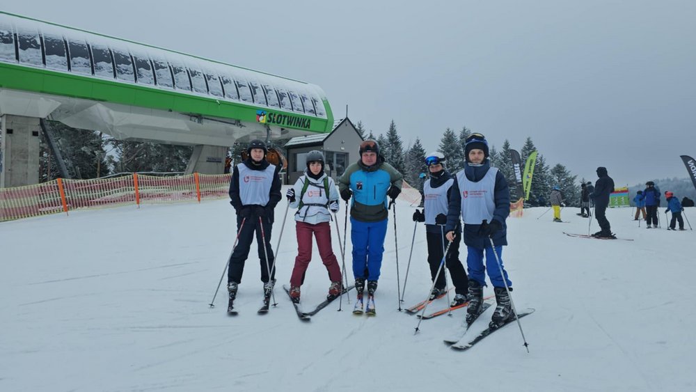 Zdjęcie trzyosobowej grupy osób na tle kompleksu narciarskiego Slotwinka