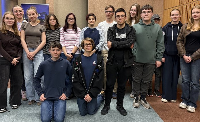 grupa młodych osób pozuje do zdjęcia w sali warsztatowej 