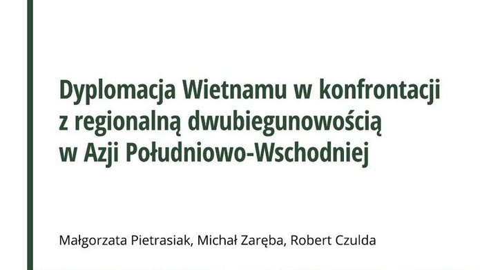 Okładka książki „Dyplomacja Wietnamu w konfrontacji z regionalną dwubiegunowością w Azji Południowo-Wschodniej”. Na okładce widoczna jest wąska kolejowa uliczka w gęsto zabudowanej części miasta w Wietnamie, z budynkami ozdobionymi flagami Wietnamu, roślinnością i muralami.