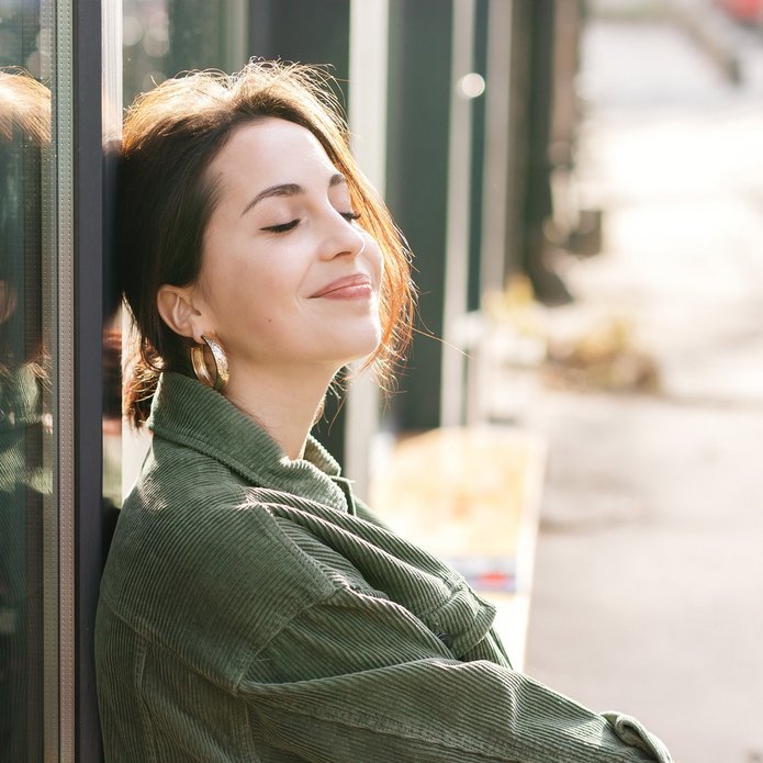 Zdjęcie zamyślonej, uśmiechającej się dziewczyny z zamkniętymi oczyma