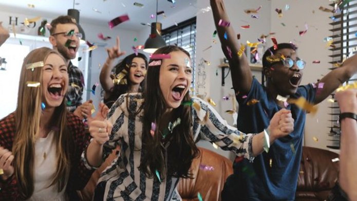 Zdjęcie przedstawiające grupę cieszących się młodych ludzi w chmurze confetti.