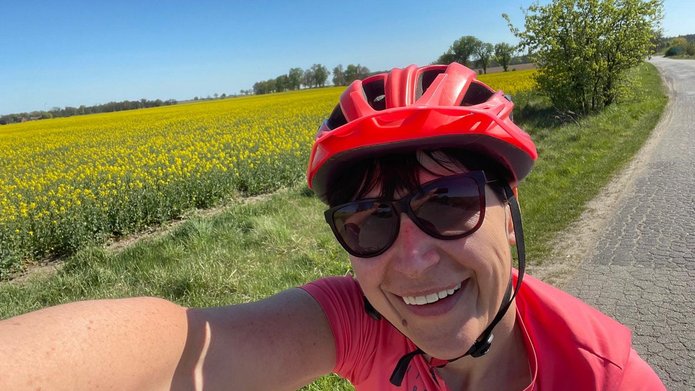 The selfie shows a person wearing a helmet against a field background
