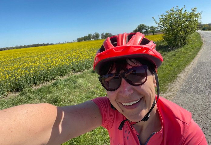 The selfie shows a person wearing a helmet against a field background