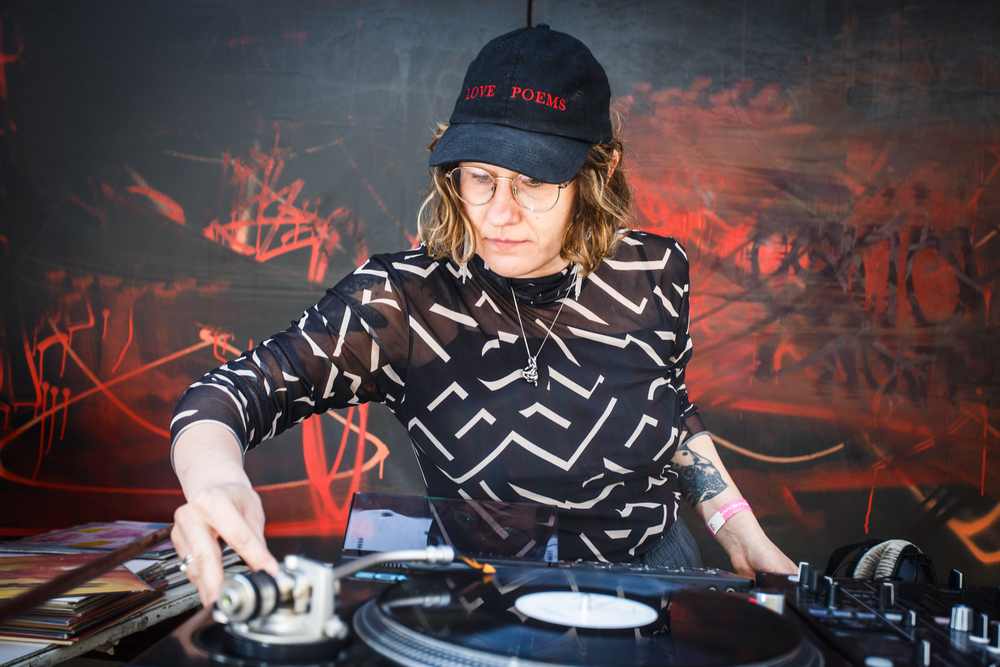 Justyna Banaszczyk - kobieta w czapce z daszkiem i okularach za stołem djskim Justyna Banaszczyk - kobieta w czapce z daszkiem i okularach za stołem djskim