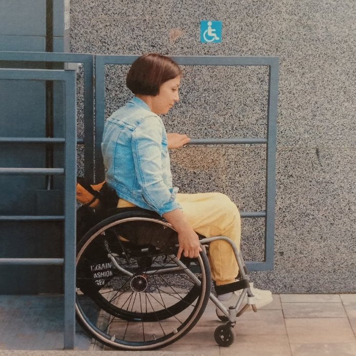 Delikatnie uśmiechająca się Studentka z niepełnosprawnością ruchową siedzi na wózku