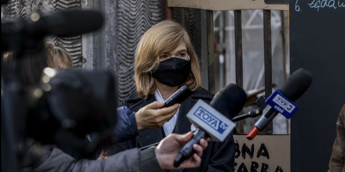 Portret rektor Żądzińskiej w maseczce, na konferencji prasowej, na tle transparentów