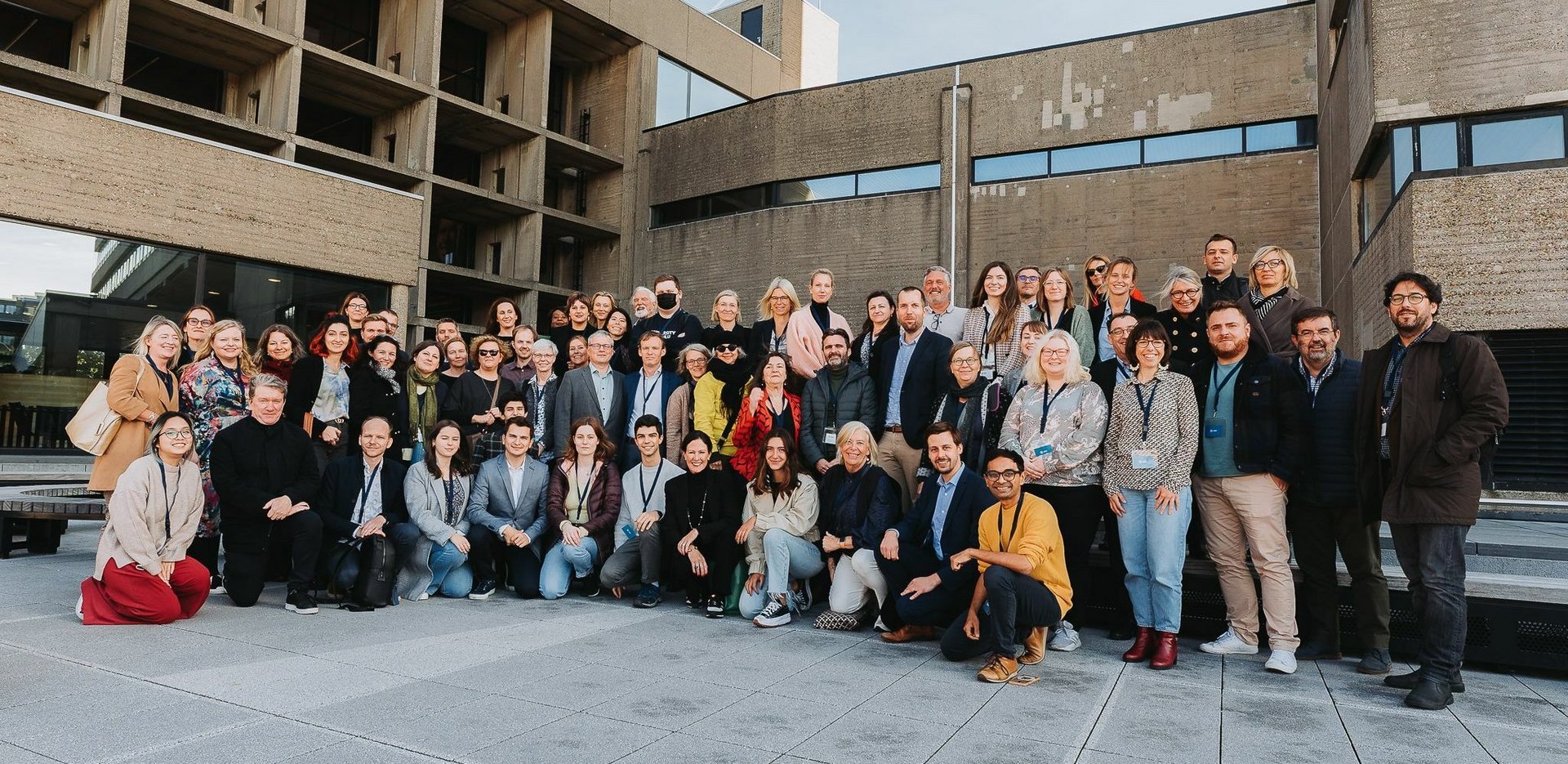 a group of participants posing against the background of beige buildings