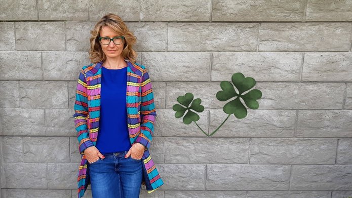 Dr hab. Małgorzata Karpińska-Krakowiak, prof. of UL posing to a photo; in the background two four-leaf clovers