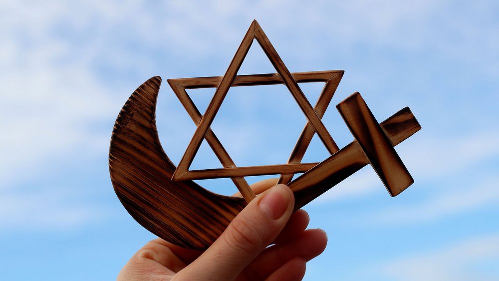 a decorative element: hands holding symbols of different religious denominations