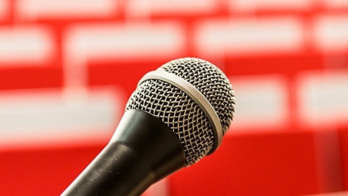 mikrofon na tle sali z pomarańczowymi krzesłami
