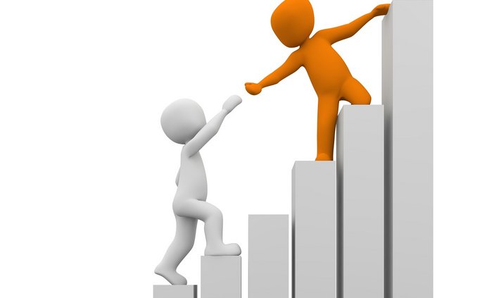 Dwóch ludzików wspina się po schodach. Ten, który jest wyżej podaje rękę w geście pomocy temu, co jest niżej. 