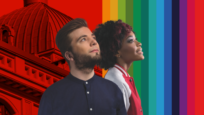 Młody mężczyzna i kobieta patrzą w górę, w tle kolorowe pionowe pasy z z grafiką przedstawiającą fragmenty budynku Rektoratu