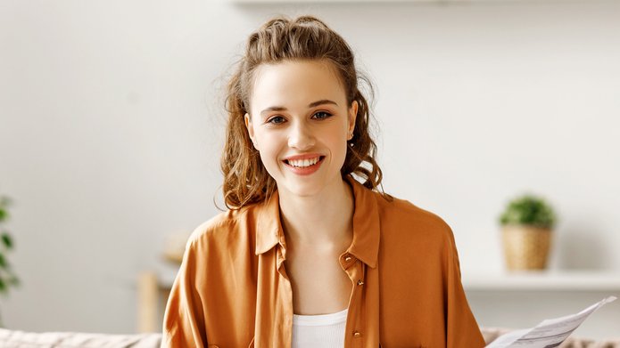 Uśmiechnięta dziewczyna w brązowej koszuli