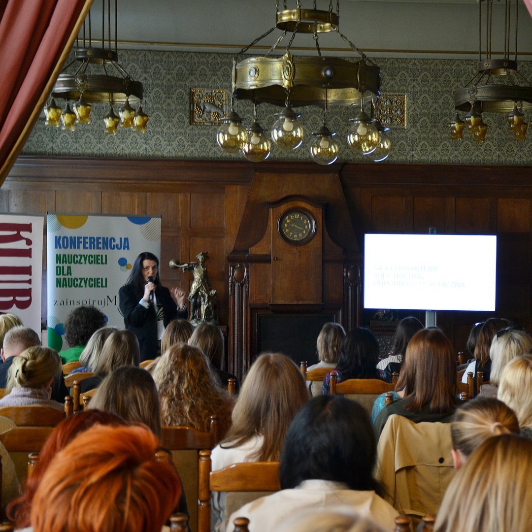 jedna z prowadzących na tle plakatu promocyjnego