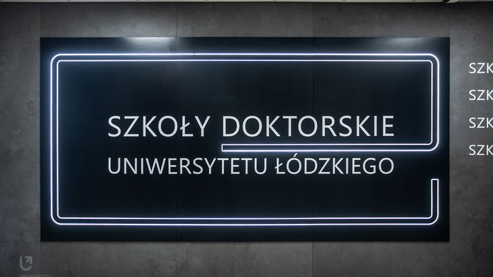 an illuminated inscription on the wall: University of Lodz Doctoral Schools