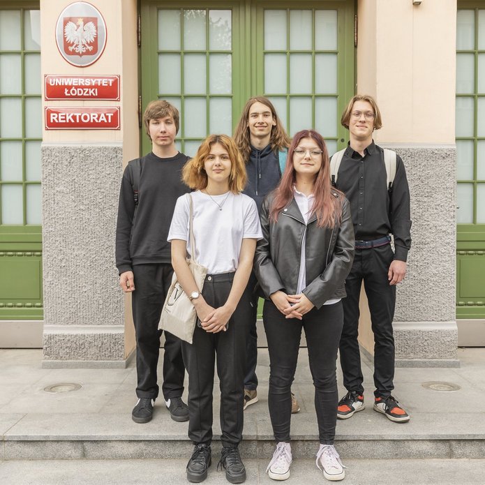 5 uczniów stojących przed budynkiem Rektoratu UŁ